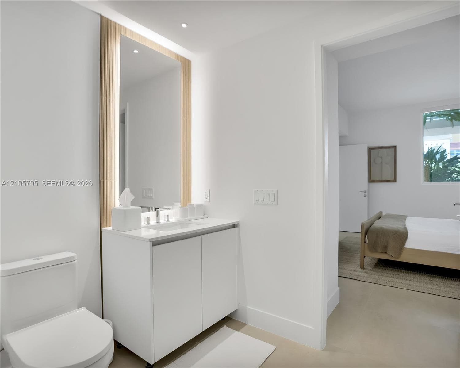 Modern vanity featuring a white cabinet, integrated countertop basin, and polished chrome faucet, accented by a full-height mirror with vertical fluted wood-finish surround and integrated LED lighting