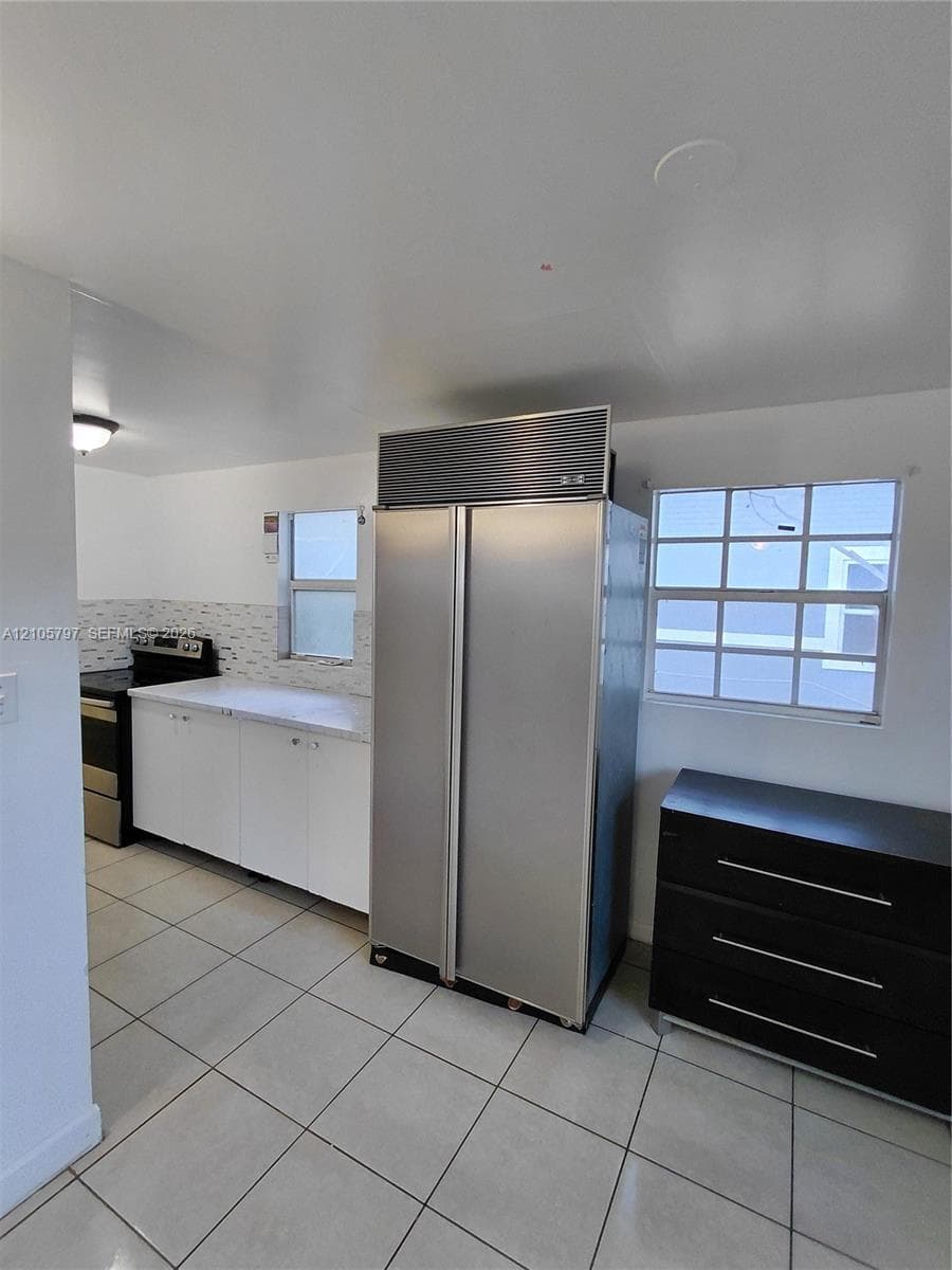 Kitchen featuring stainless steel dual-door refrigerator, smooth-surface countertops, tile flooring