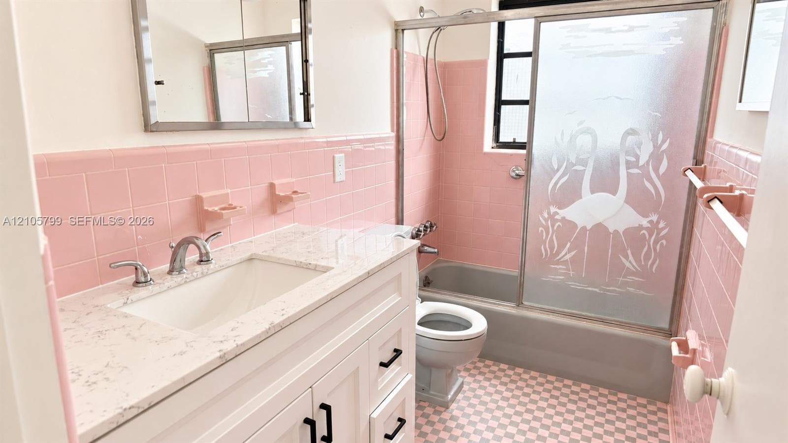 Bathroom featuring a white vanity with a composite countertop, ceramic wall tiling, a bathtub with an etched-glass sliding door, and checkered flooring