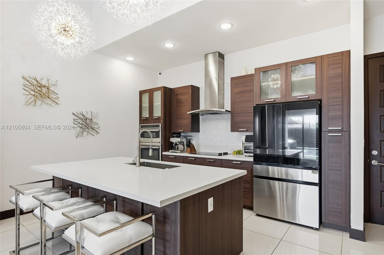 Kitchen featuring custom wood-finish cabinetry, a large central island with a quartz countertop, stainless steel appliances, a glass-tile backsplash, and recessed lighting