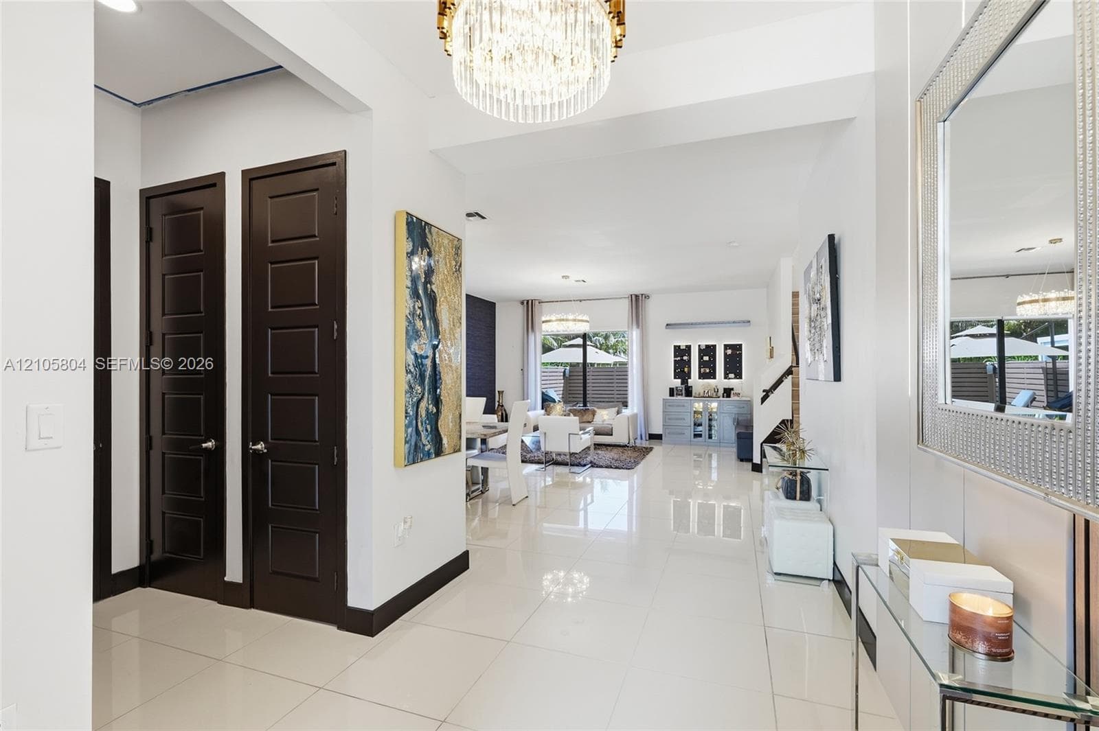 Polished porcelain tile flooring, dark-toned six-panel interior doors, and a multi-tiered crystal drum chandelier
