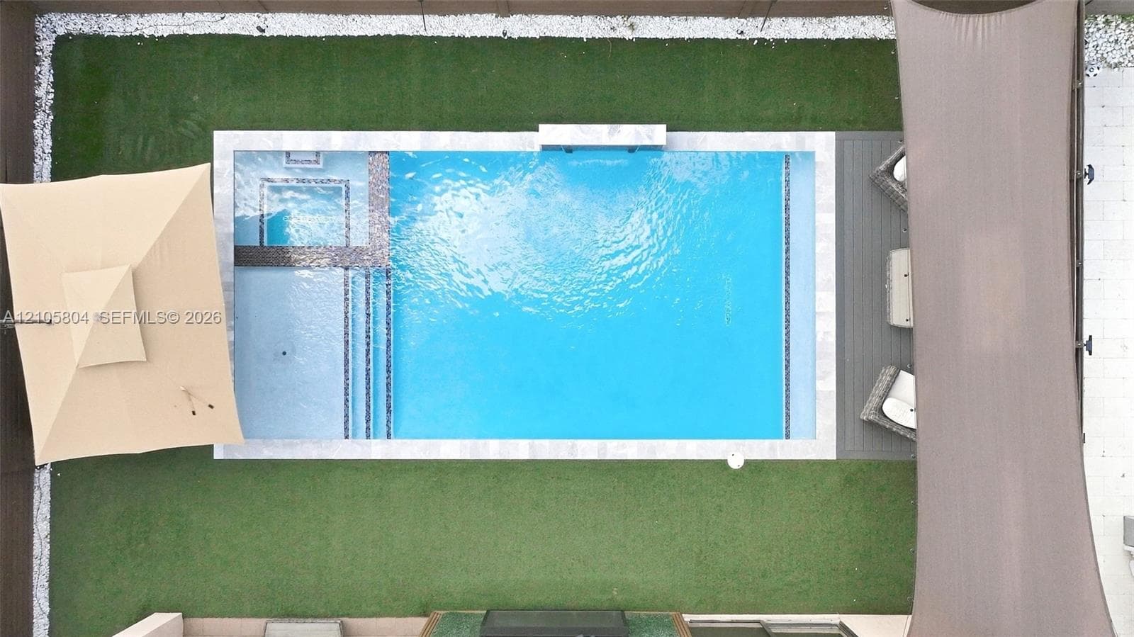 Outdoor area featuring an in-ground pool with a built-in spa, stone-finish coping, synthetic turf landscaping, and a composite deck surface