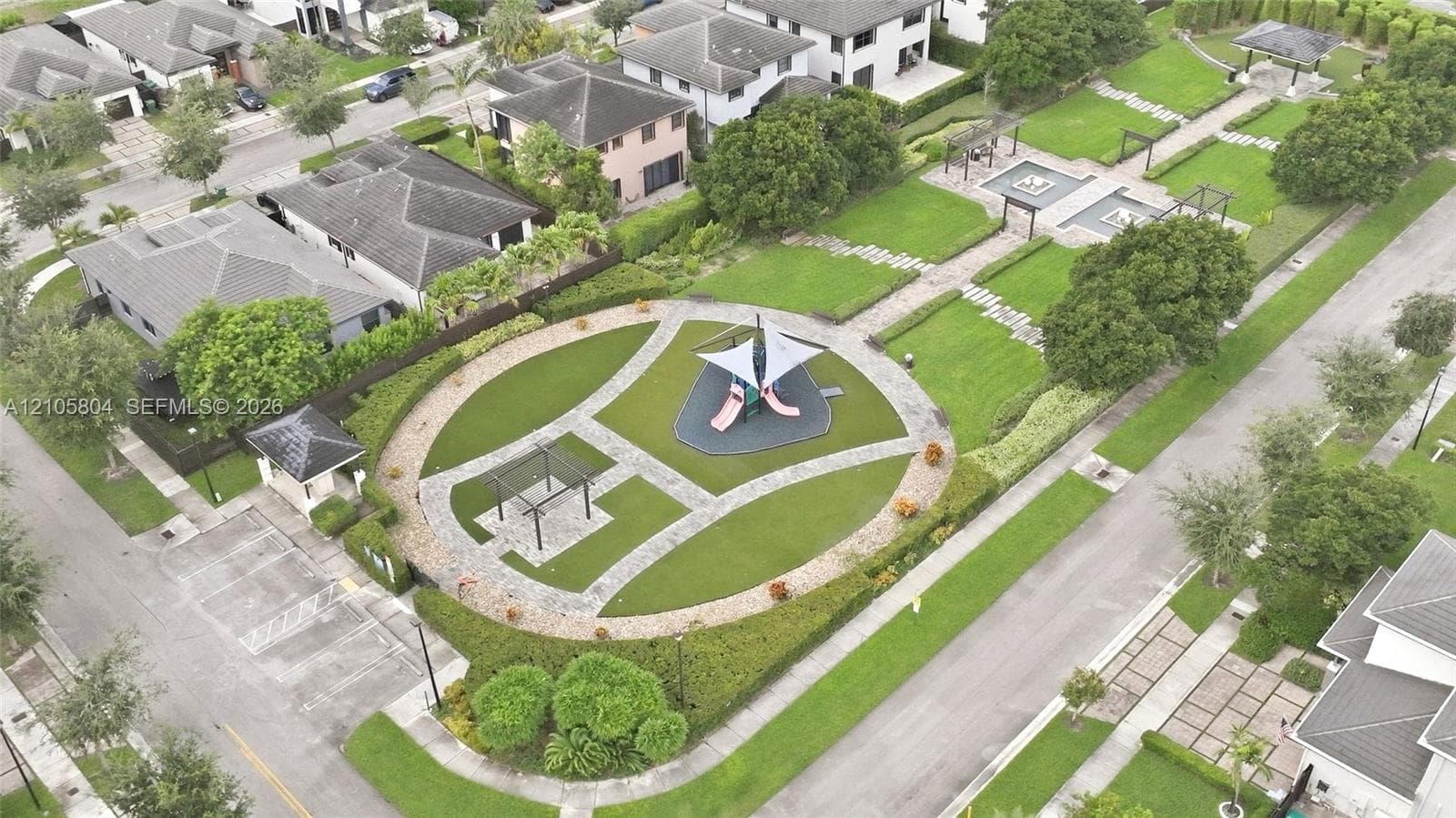 Expansive outdoor grounds featuring manicured lawns, paved pathways, a covered playground structure, multiple pergolas, and structured hedges