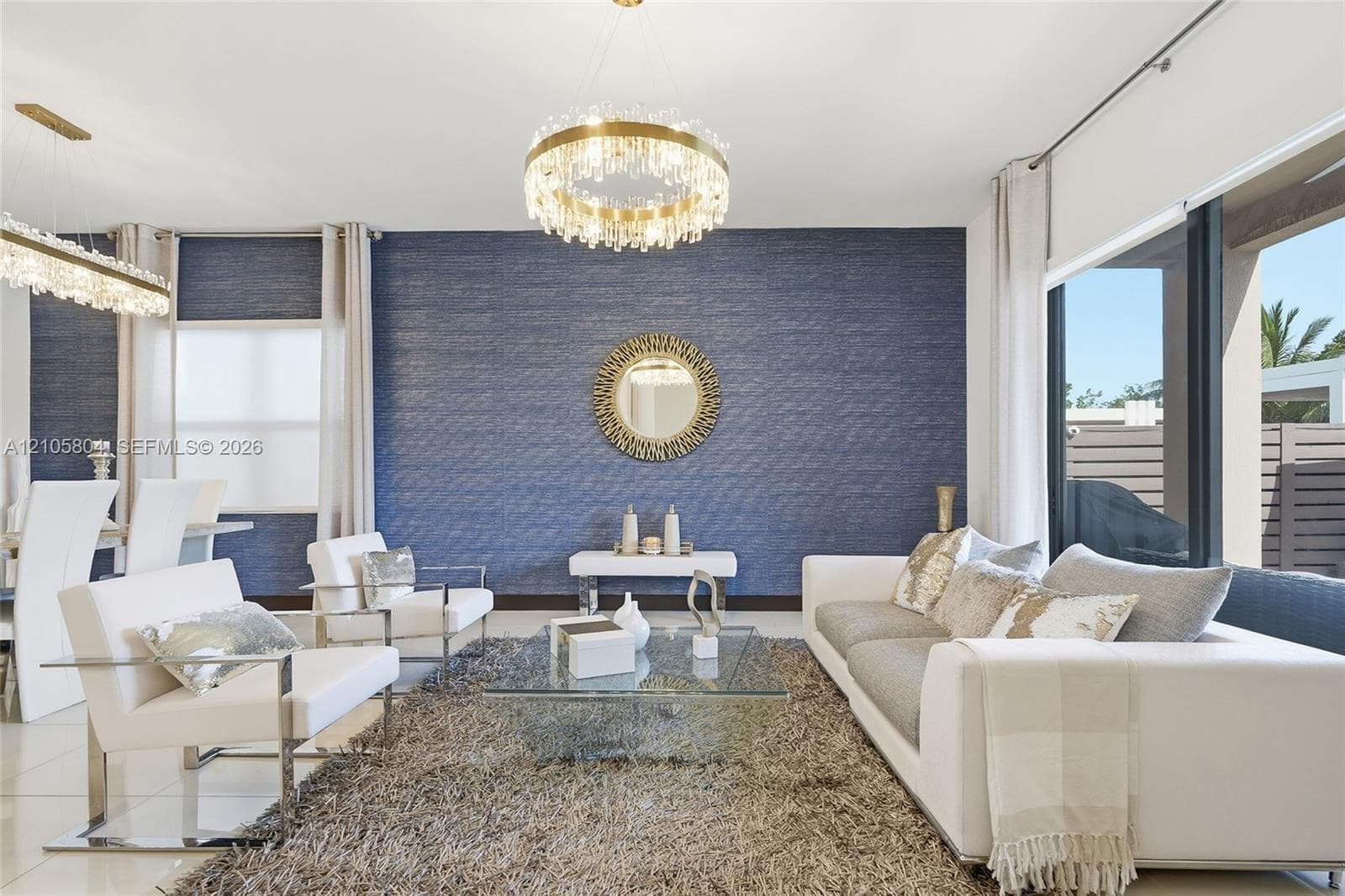 Textured blue accent wall featuring a contemporary crystal drum chandelier, large-format tile flooring, and oversized windows