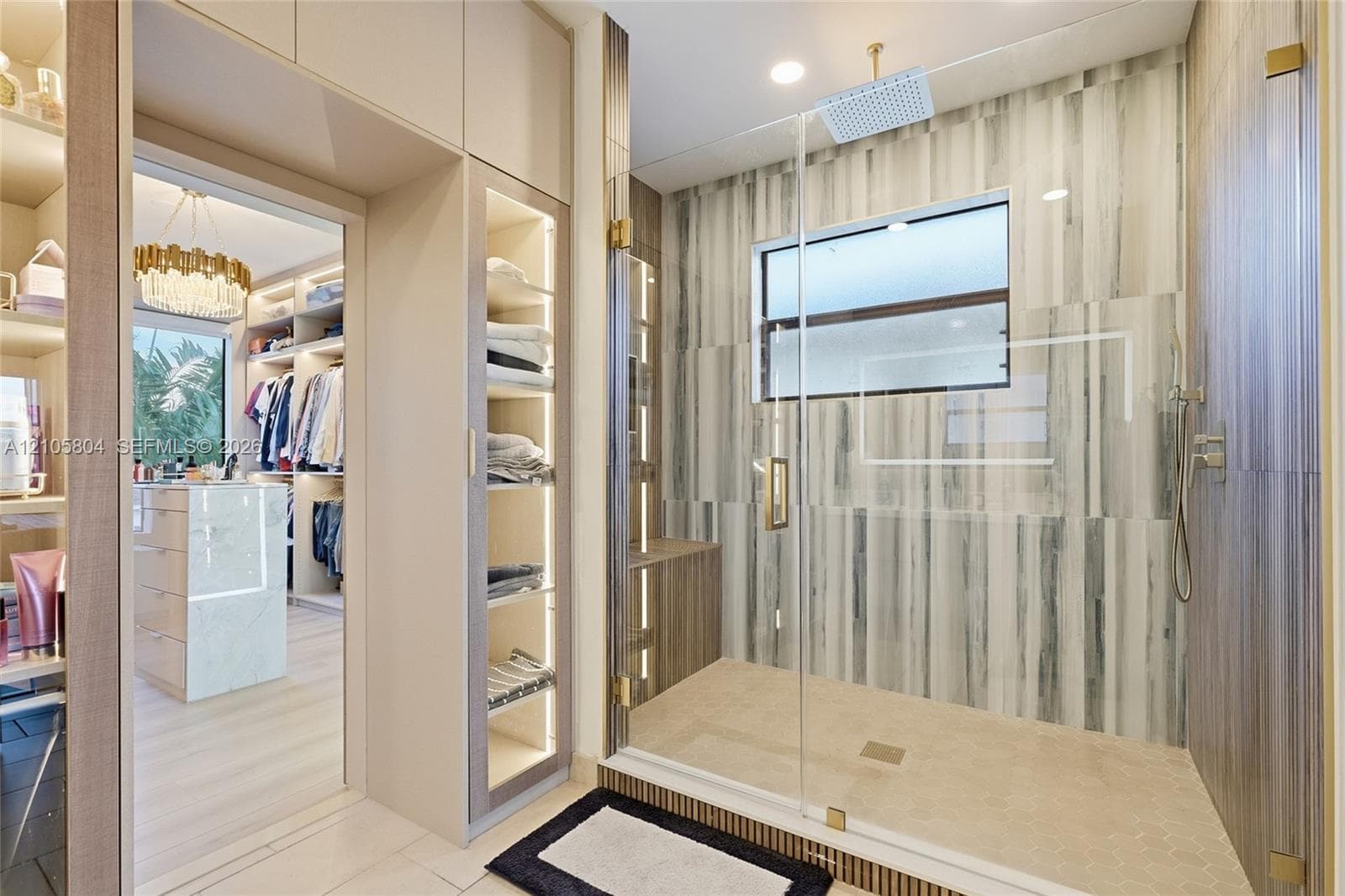 Walk-in shower with floor-to-ceiling tiled walls, glass enclosure, and rainfall showerhead, complemented by custom built-in cabinetry with integrated lighting