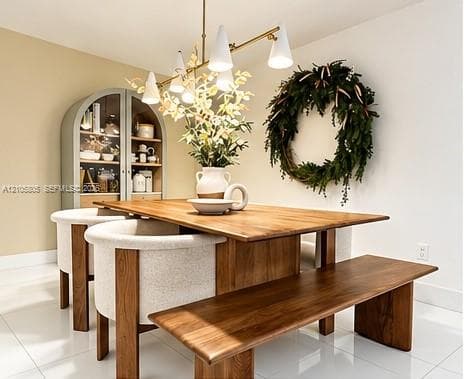 Built-in arched glass-front cabinetry with wood-tone interior, matte gold-finish multi-light chandelier, and polished tile flooring