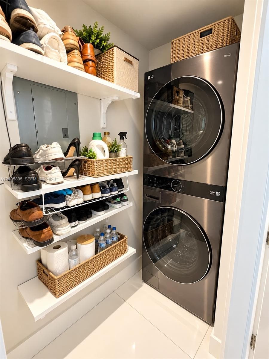 Laundry area featuring a stainless steel stacked washer and dryer unit, wall-mounted shelving with integrated brackets, and polished tile flooring