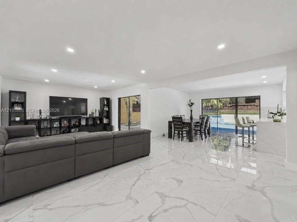Open-concept floor plan featuring large-format veined tile flooring, recessed ceiling lighting, and sliding glass doors to the exterior