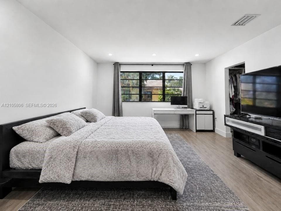 Neutral-toned room featuring wood-finish flooring, recessed lighting, and multi-pane window with dark frames