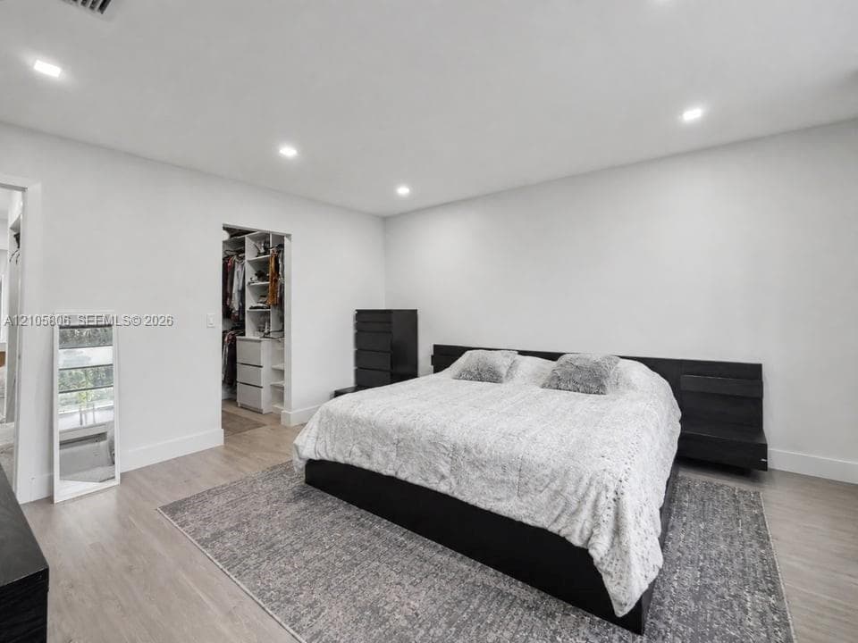 Bedroom featuring wood-finish flooring, recessed lighting, and a built-in walk-in closet with integrated shelving