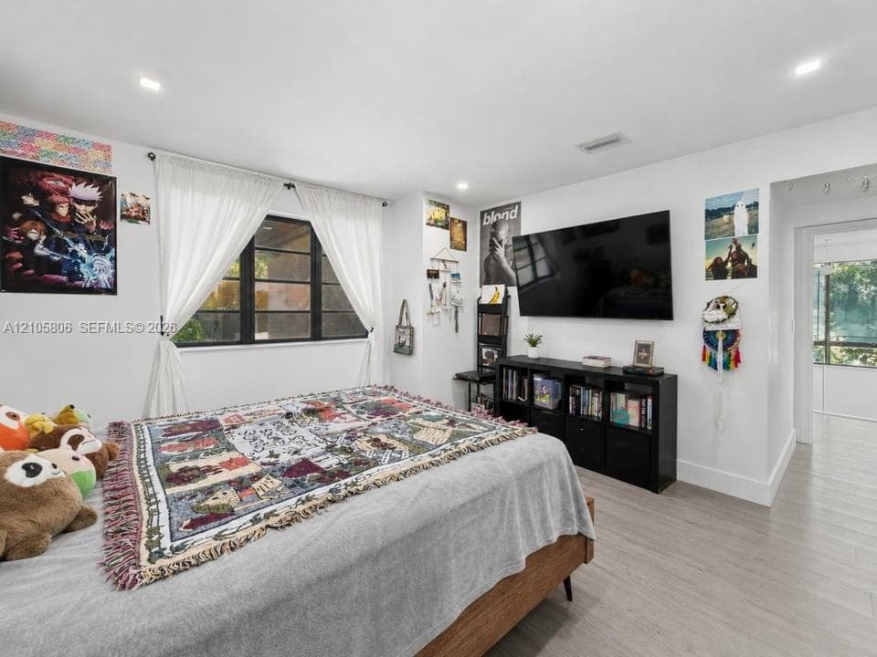 Neutral-toned wood-finish flooring, recessed lighting, and expansive window with dark-framed panes