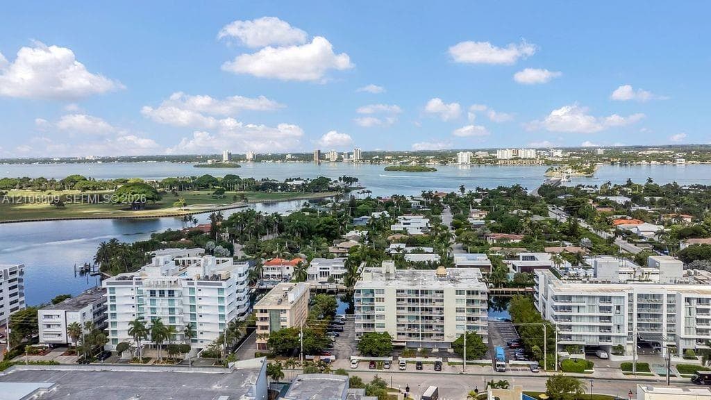 Aerial perspective of coastal residential area featuring deep-water bay frontage, mature tropical landscaping, and multi-story structural developments