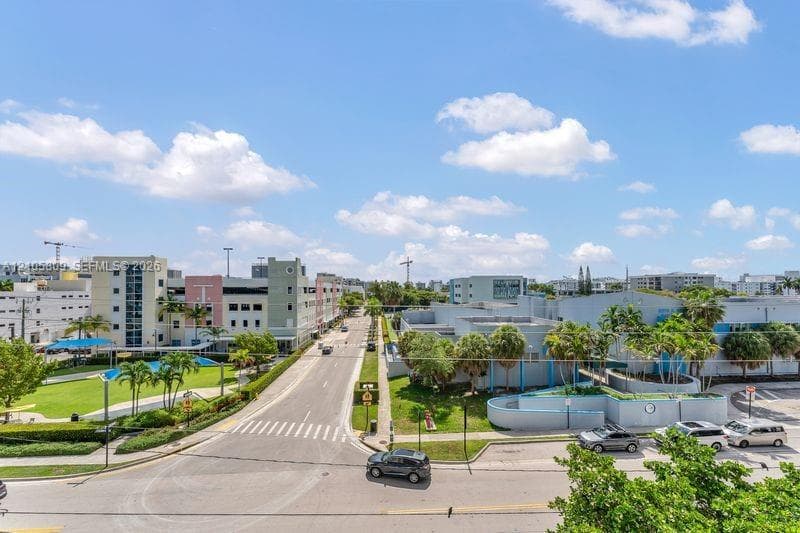 Aerial perspective featuring paved public roadways, established perimeter landscaping, groomed grass surfaces, and proximity to municipal infrastructure and local thoroughfares