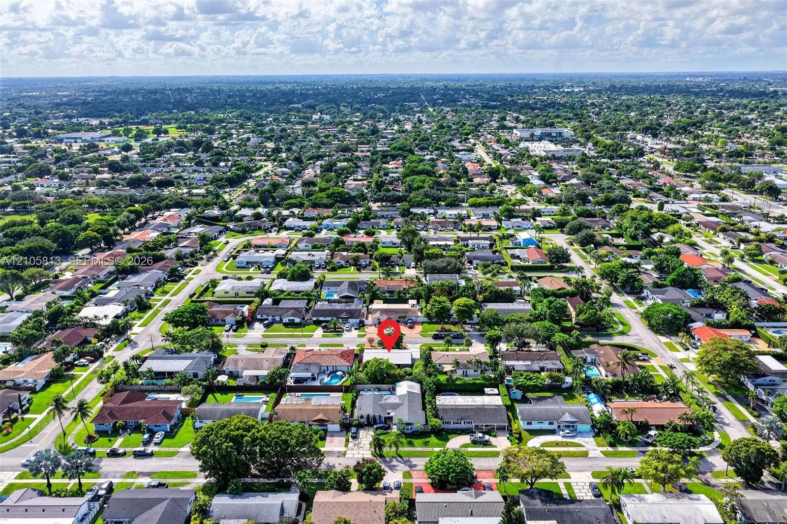 Aerial perspective of a residential property situated in a developed suburban neighborhood featuring mature canopy trees and established landscaping