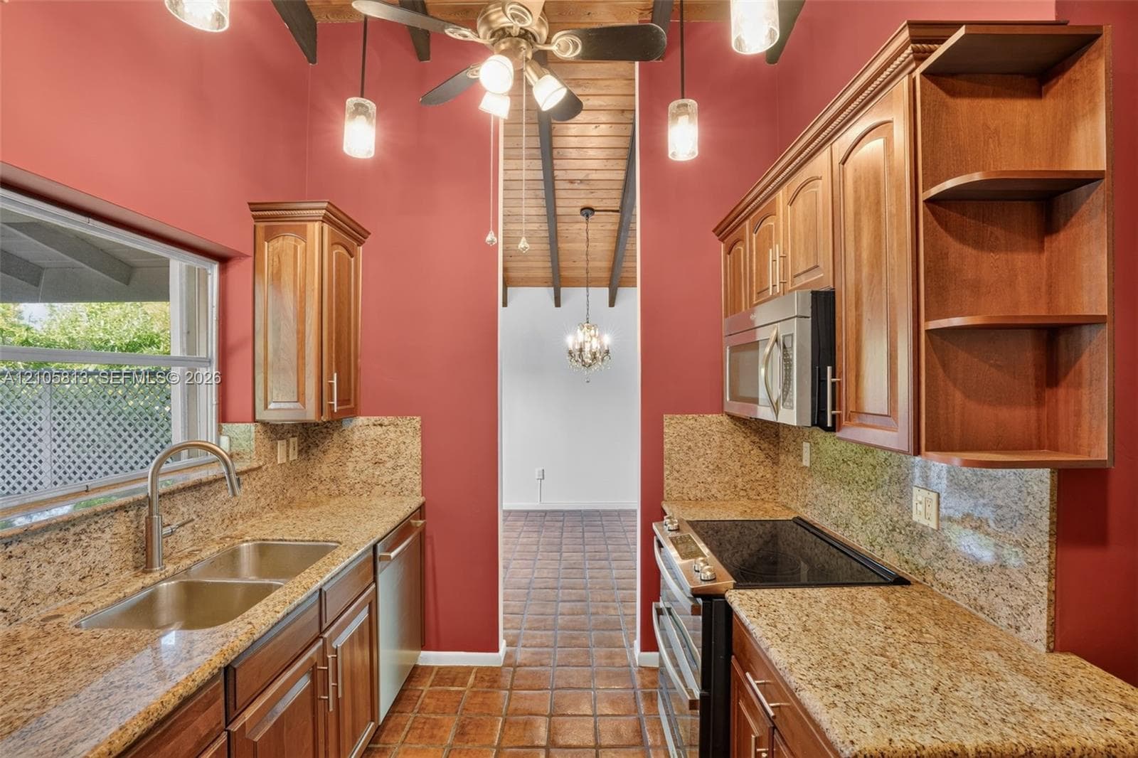 Kitchen featuring wood cabinetry, stone-surface countertops, tile flooring, and a vaulted ceiling with exposed beams