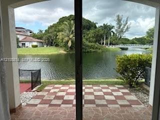 Patio featuring a checkered stone tile inlay, arched sliding glass entry doors, and waterfront access