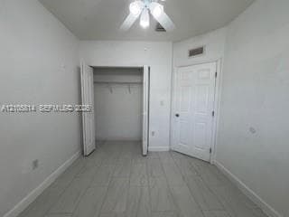 Interior room featuring light-toned tile flooring, a dual-door closet, a six-panel door, and a ceiling fan with integrated lighting