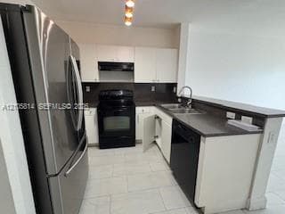 Kitchen featuring white cabinetry, dark stone-finish countertops, stainless steel refrigerator, black appliance suite, and ceramic tile flooring