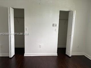 Dual walk-in closets with bi-fold doors and wood-finish flooring