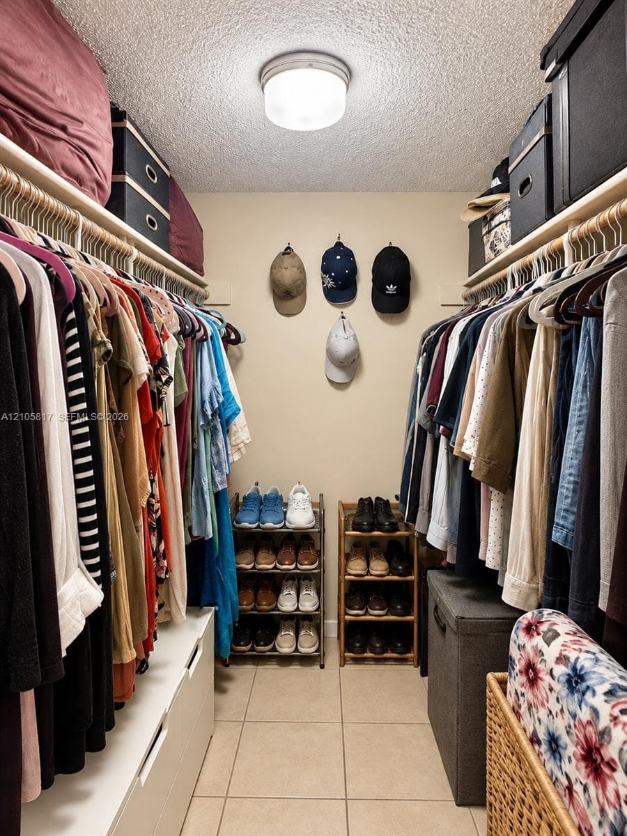 Walk-in closet featuring dual-sided hanging rods, built-in shelving, tile flooring, and flush-mount overhead lighting