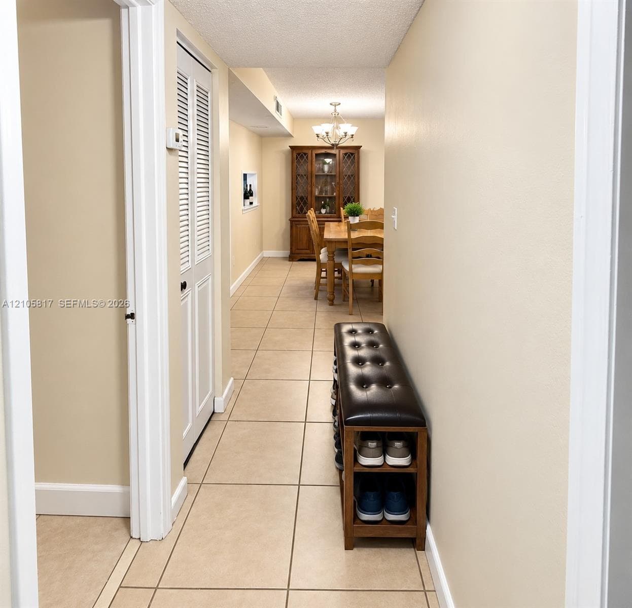 Hallway featuring neutral-toned tile flooring, louvered closet doors, and a recessed wall niche