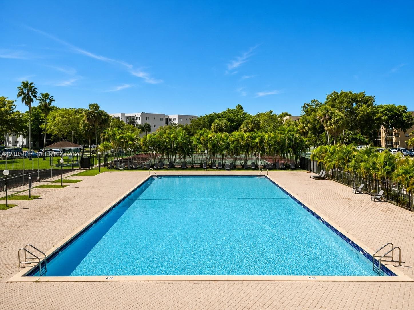 Rectangular swimming pool with metal ladder access points and expansive paver deck