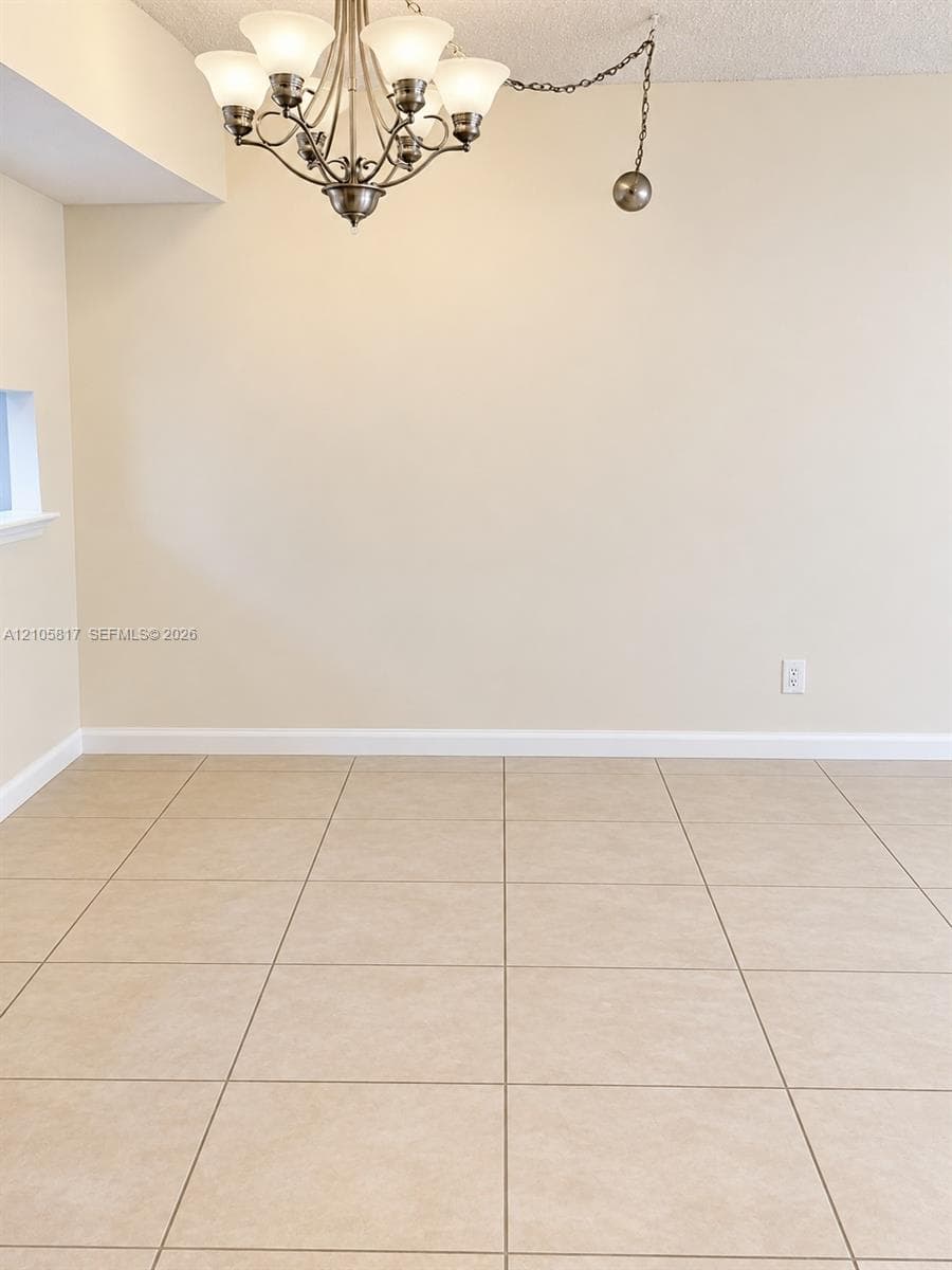Neutral-toned ceramic tile flooring paired with a multi-arm chandelier featuring frosted glass shades and a metallic finish