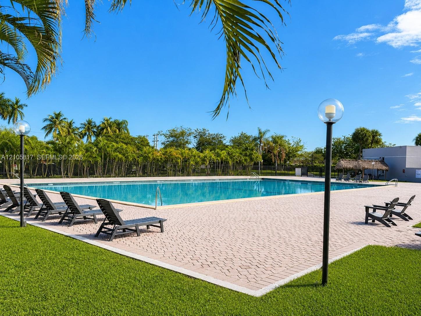 Swimming pool with paver decking, pole-mounted globe lighting, and landscaped greenery