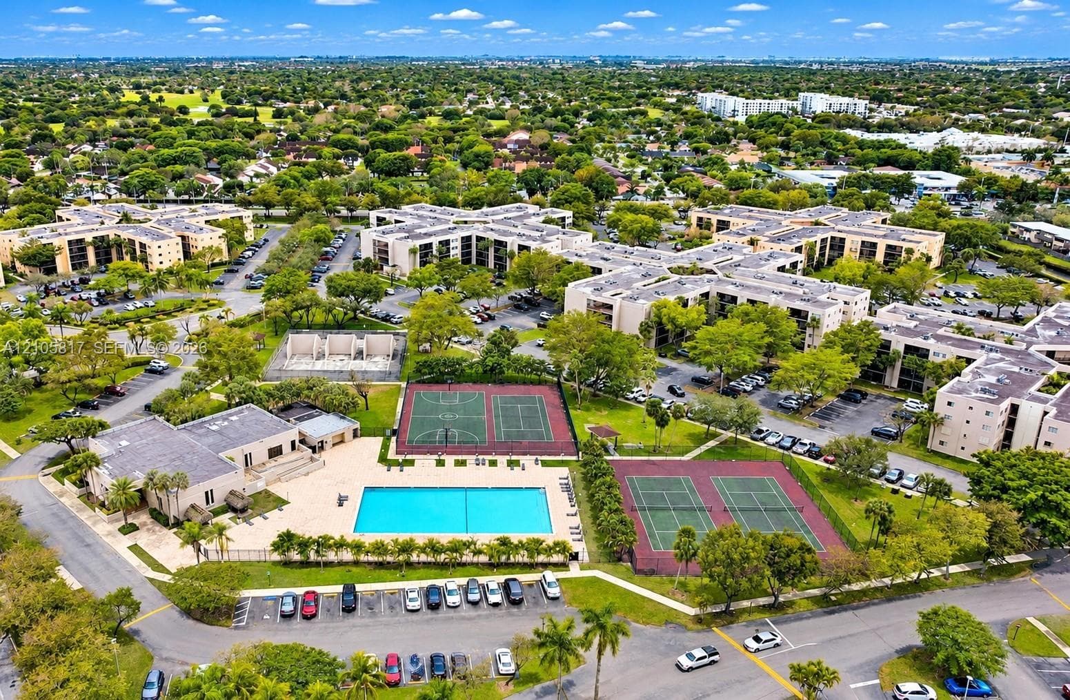 Aerial perspective featuring an outdoor swimming pool, two tennis courts, and a basketball court within a landscaped community grounds