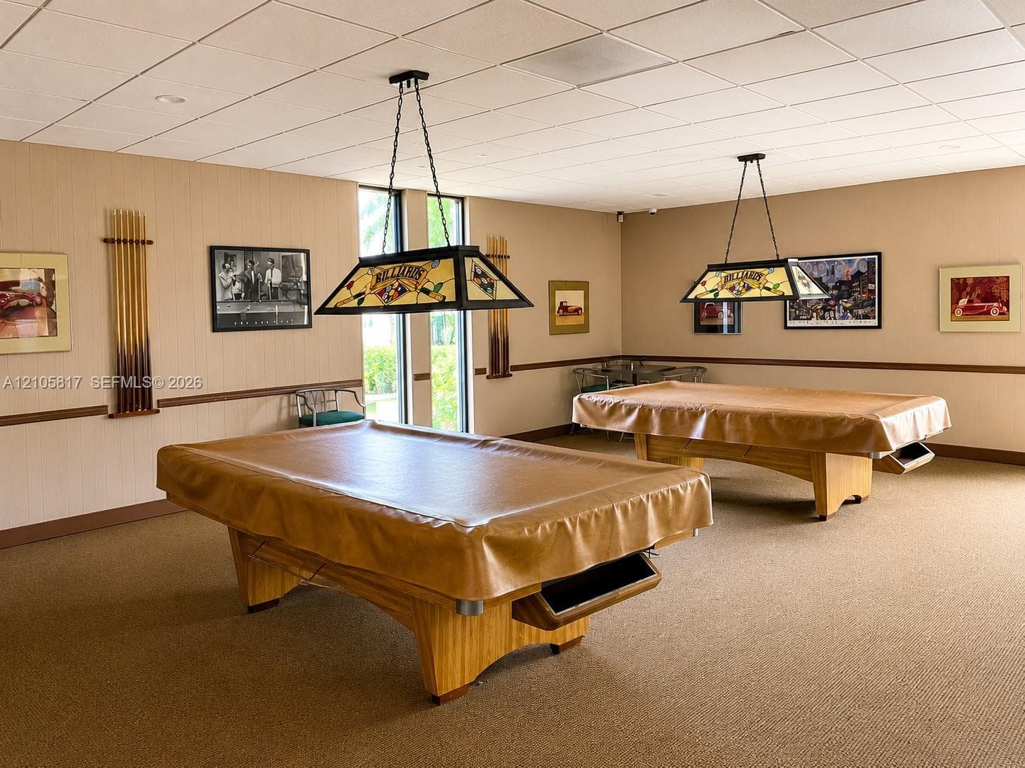 Room featuring neutral wall covering with chair rail molding, drop ceiling, and dual decorative billiard-style pendant light fixtures