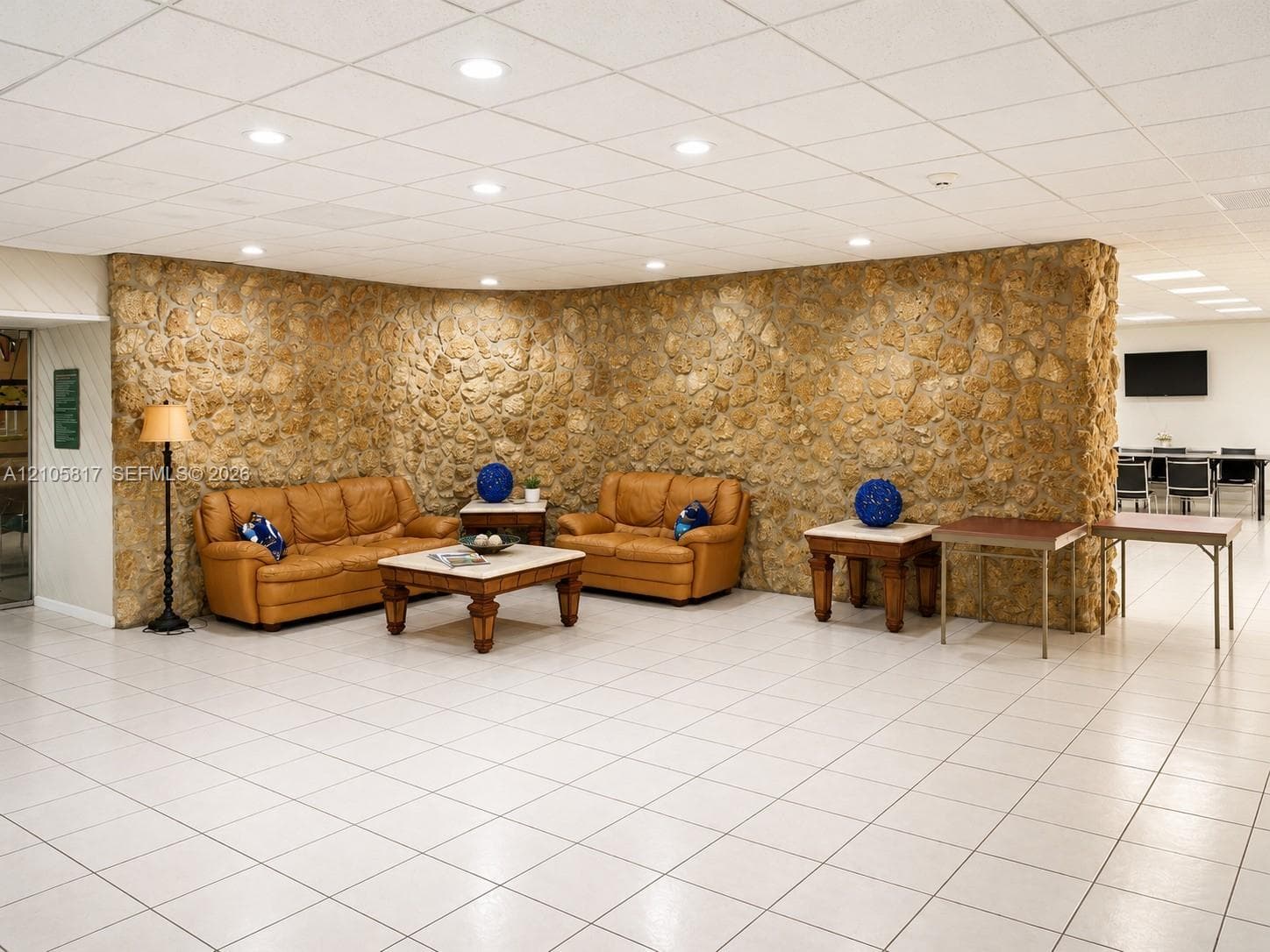 Expansive room featuring a curved stone accent wall, neutral ceramic tile flooring, and recessed ceiling lighting