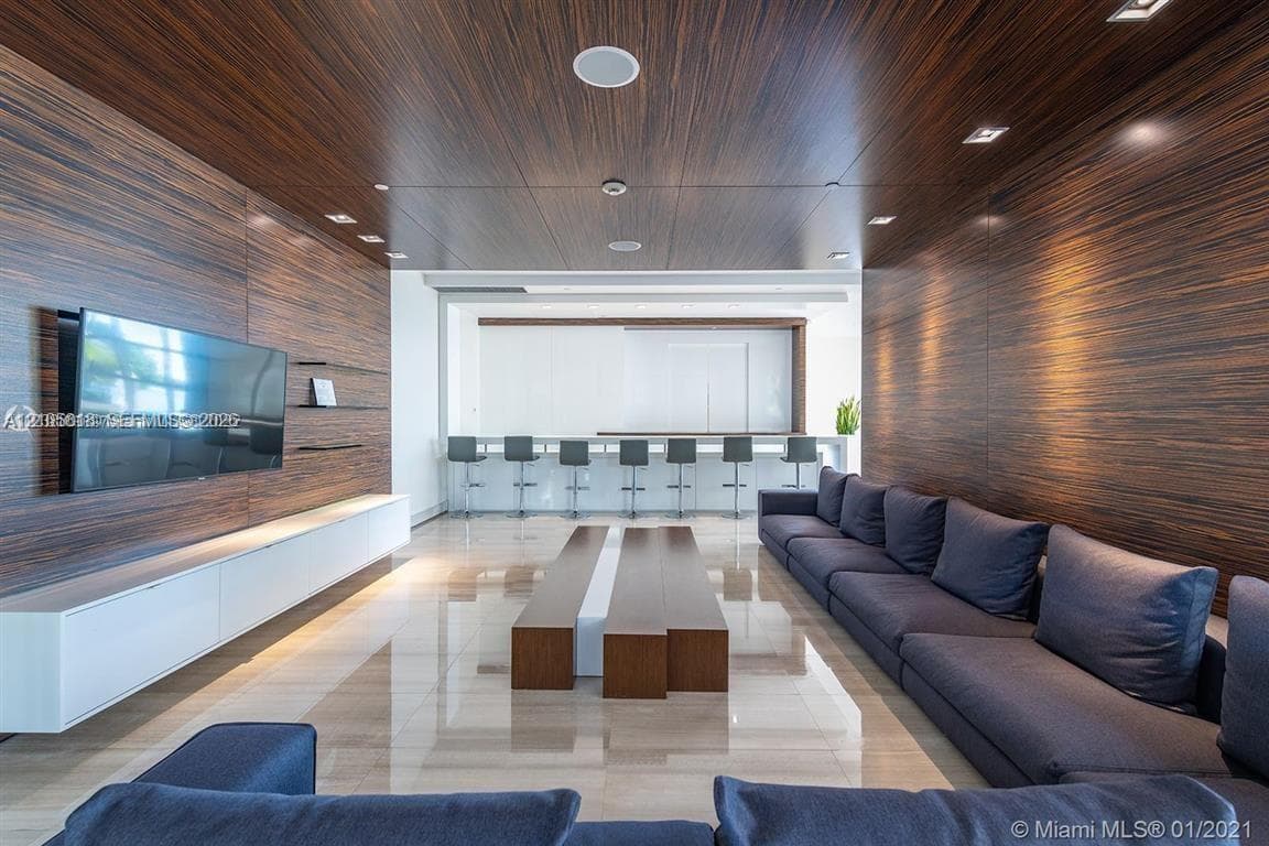Interior space featuring horizontal wood-finish wall and ceiling paneling, polished stone flooring, recessed lighting, and a built-in wall-mounted media console