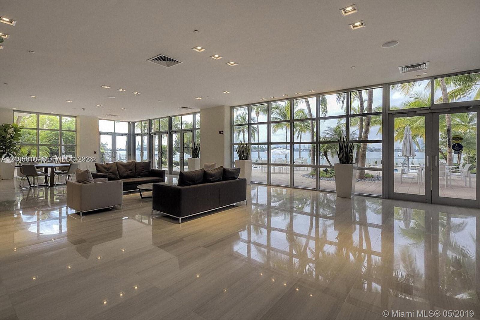 Expansive interior featuring polished stone flooring, floor-to-ceiling glass wall panels, and recessed ceiling lighting
