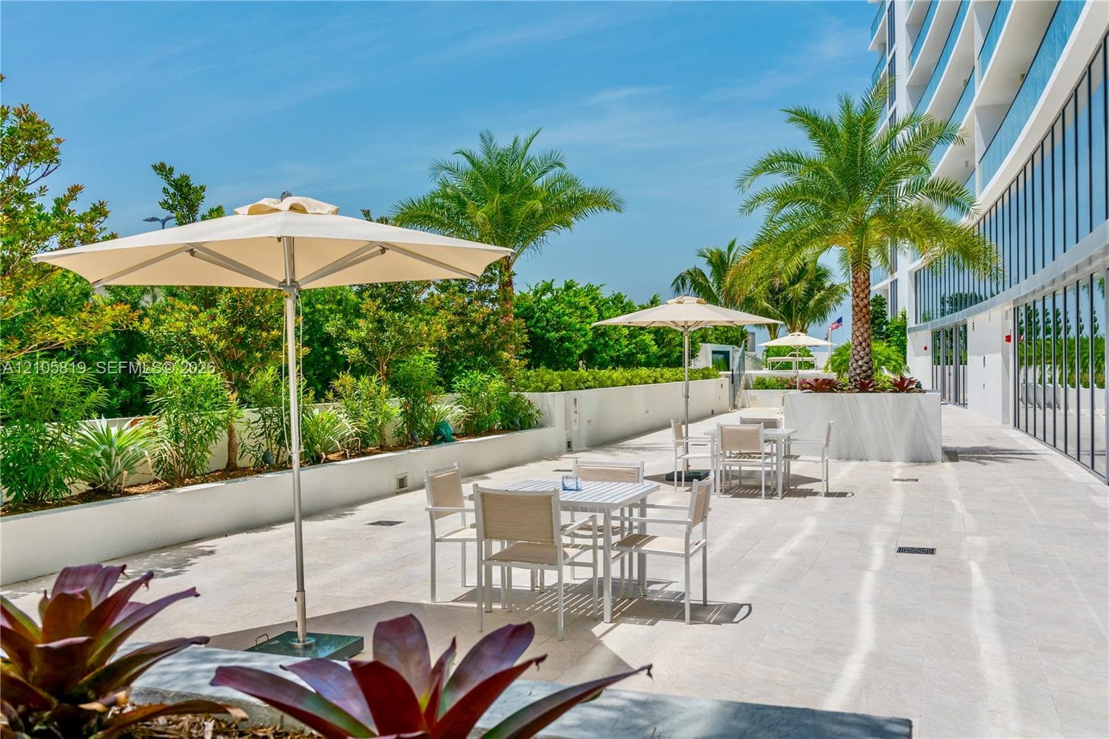 Outdoor terrace featuring stone-finish flooring, integrated concrete planters, and mature palm landscaping