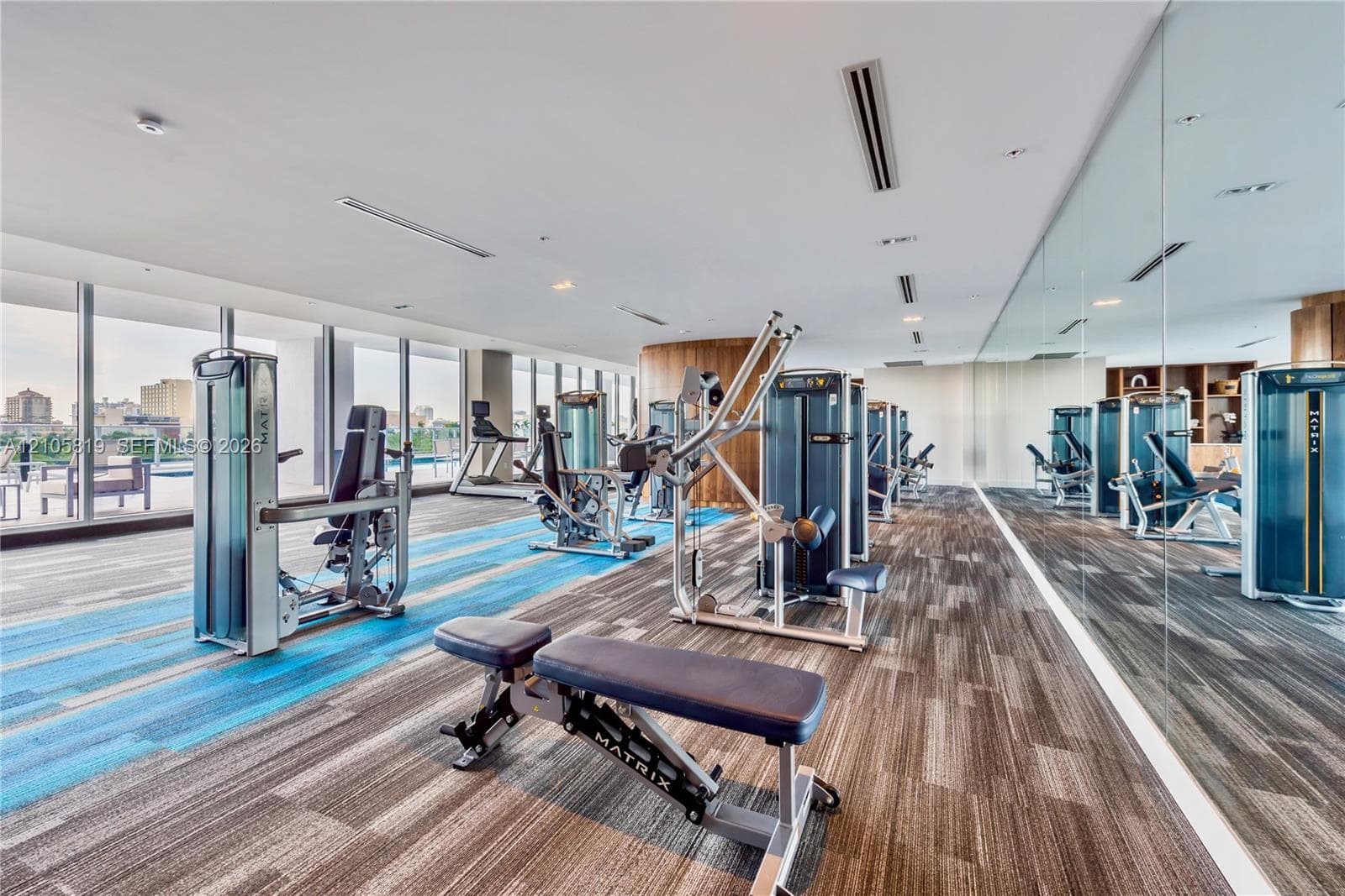 Fitness center featuring floor-to-ceiling windows, full-length wall mirrors, and patterned carpeting