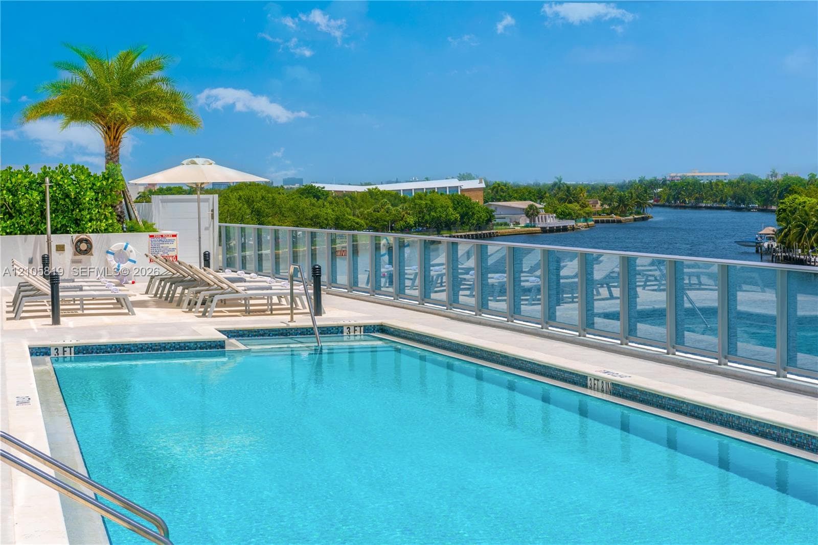 Heated Swimming pool with tile surround, glass panel railing, and paved sun deck