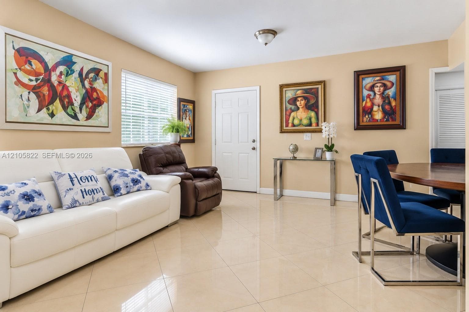 Neutral-toned interior space featuring polished tile flooring, white six-panel entry door, and horizontal blinds