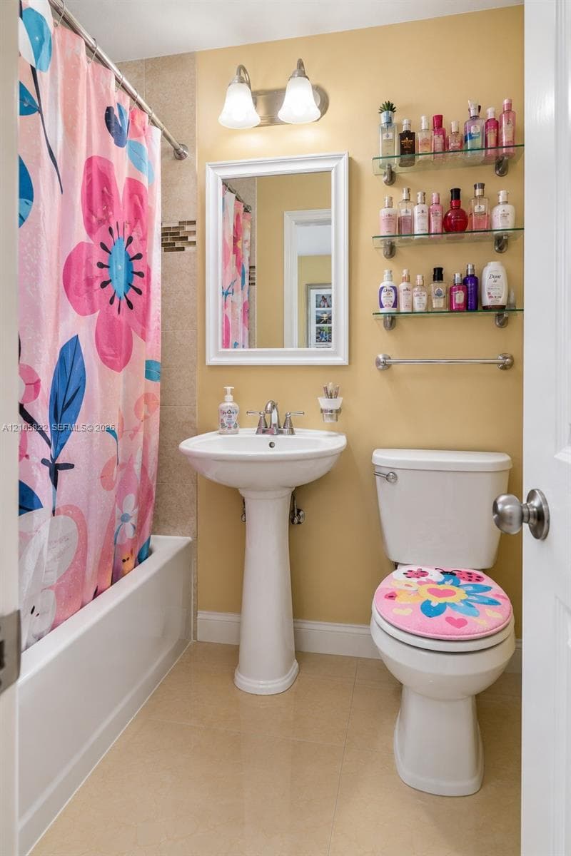 White pedestal sink with chrome faucet, wall-mounted rectangular mirror, dual-light vanity fixture, tile flooring, and three integrated glass shelving units