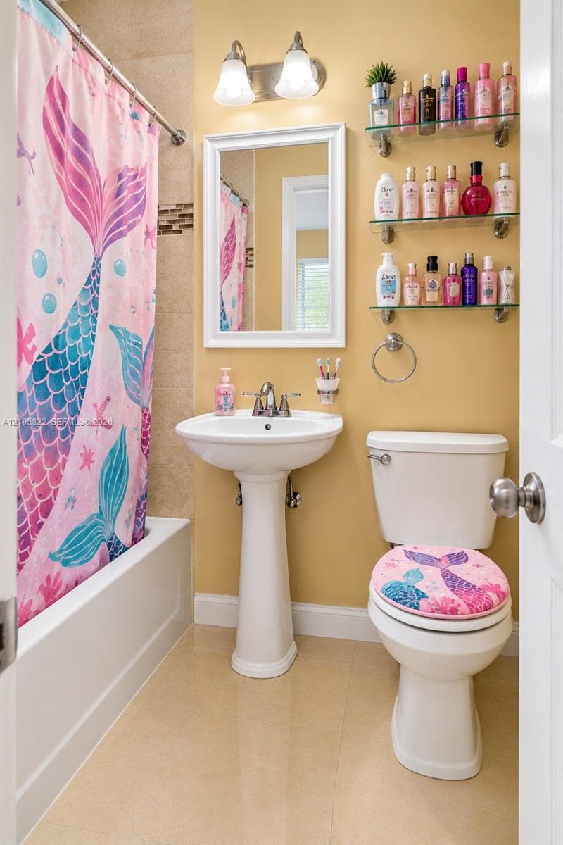 Bathroom featuring a white pedestal sink with a dual-handle faucet, a framed wall mirror, polished light-toned floor tile, a tiled shower surround, and built-in glass shelving
