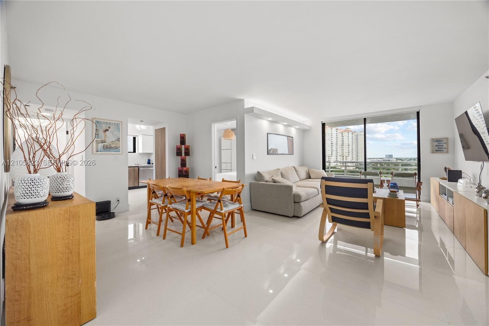 Open-concept living space featuring large-format tile flooring, built-in recessed lighting, floor-to-ceiling sliding glass doors, and a custom built-in media console