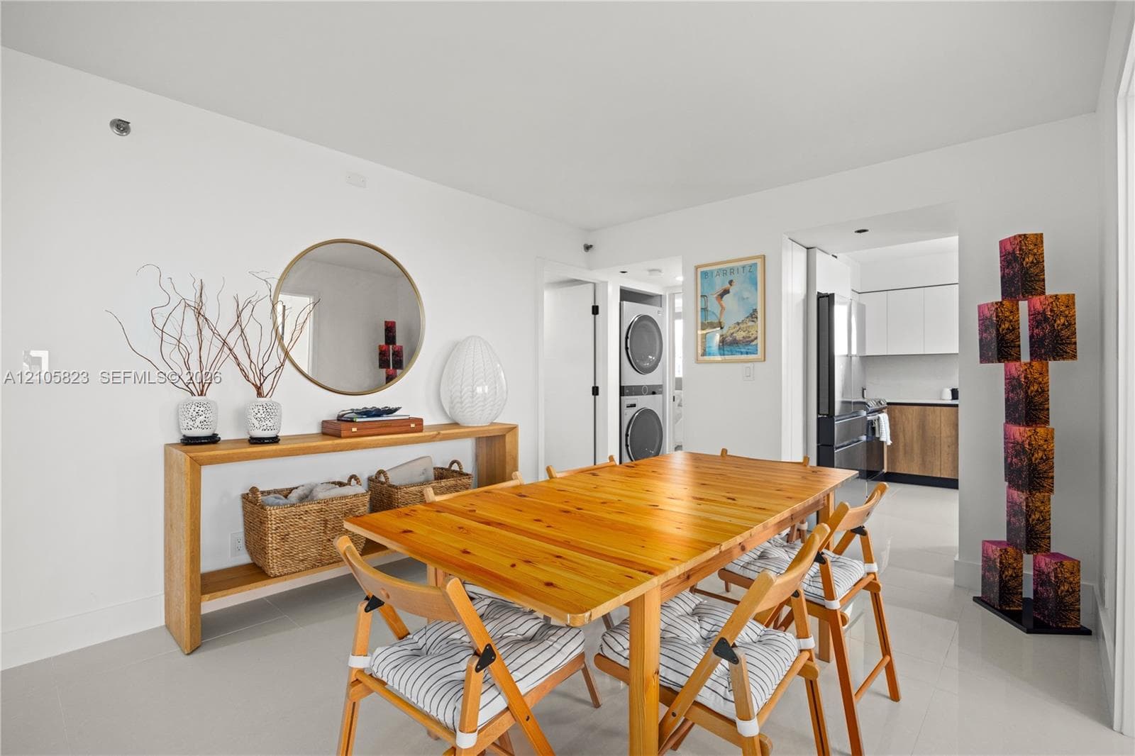 Dining area featuring white walls, neutral large-format tile flooring, and a stacked washer and dryer unit