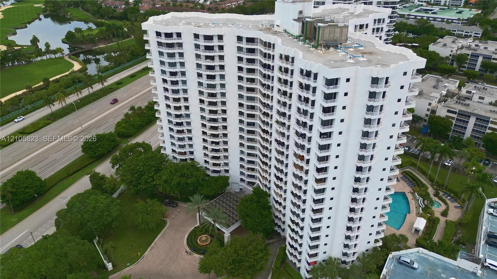 High-rise residential building featuring private balconies, a circular driveway with a central fountain, and an outdoor swimming pool with a spa