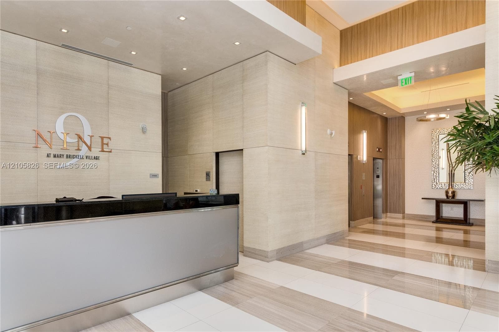 Lobby featuring a reception desk with a black countertop and metallic base, floor-to-ceiling textured wall paneling, recessed lighting, and large-format tile flooring