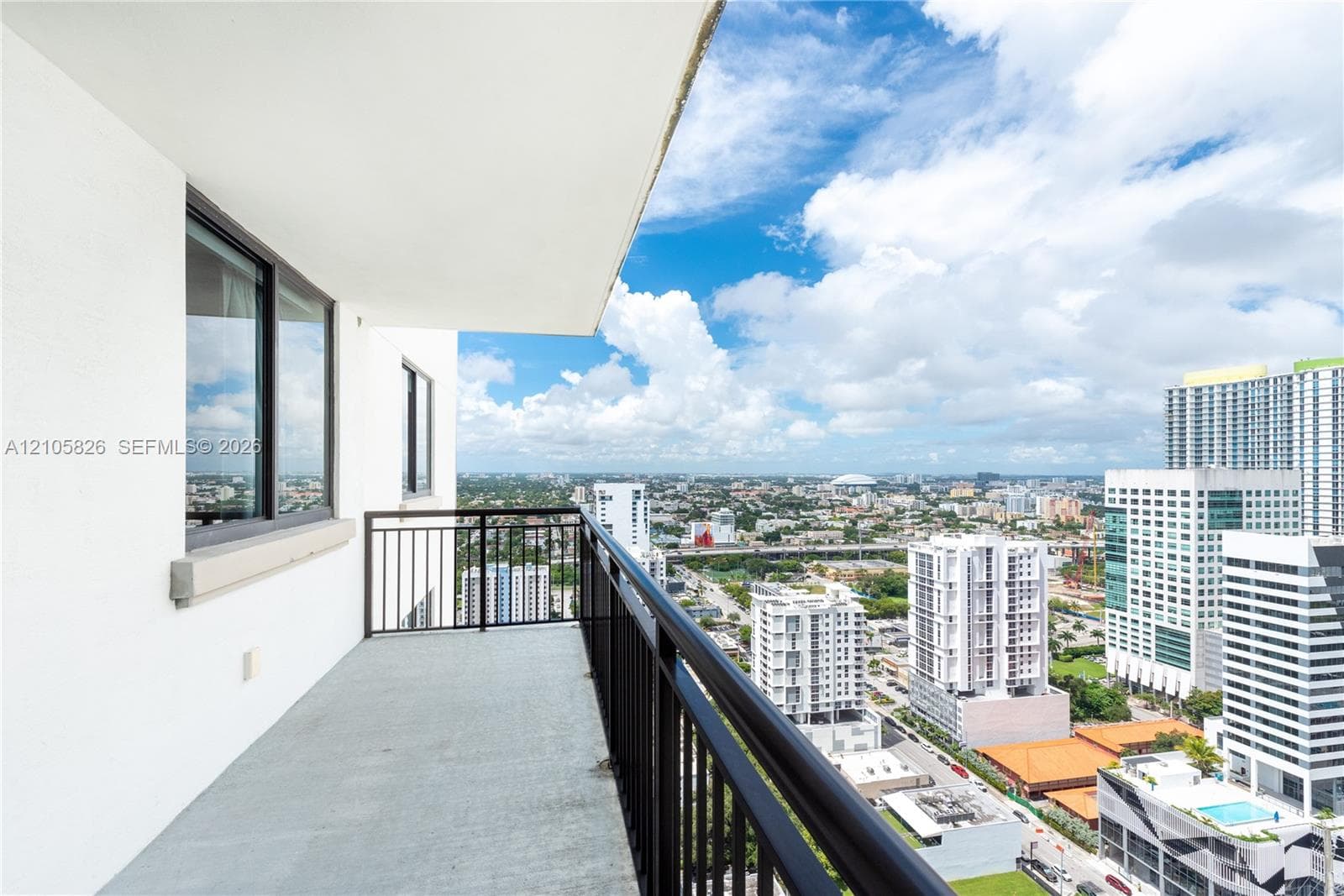 Private balcony featuring metal railings, overhead soffit, and concrete flooring