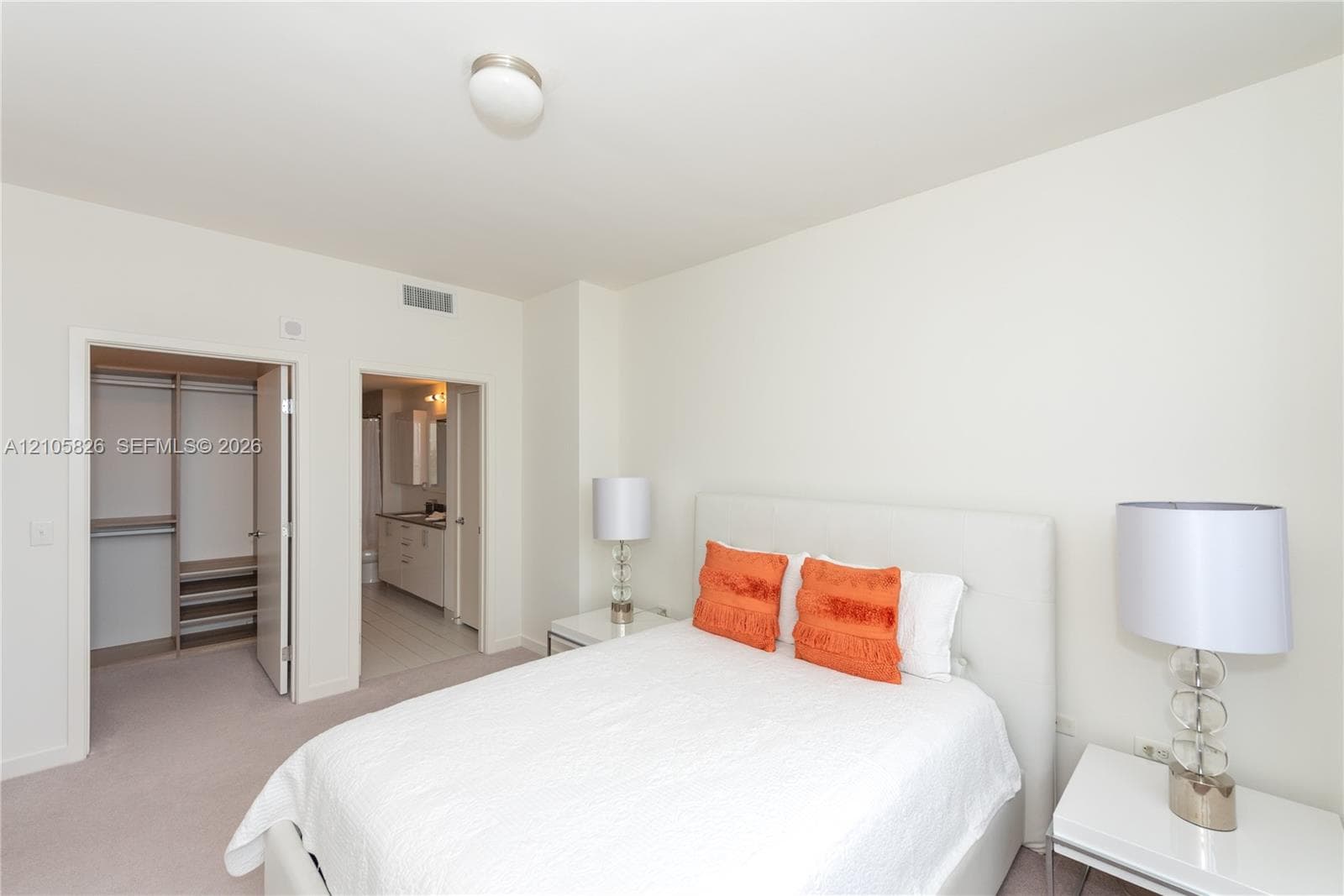 Carpeted flooring, walk-in closet with built-in shelving, and attached full bathroom with vanity cabinet