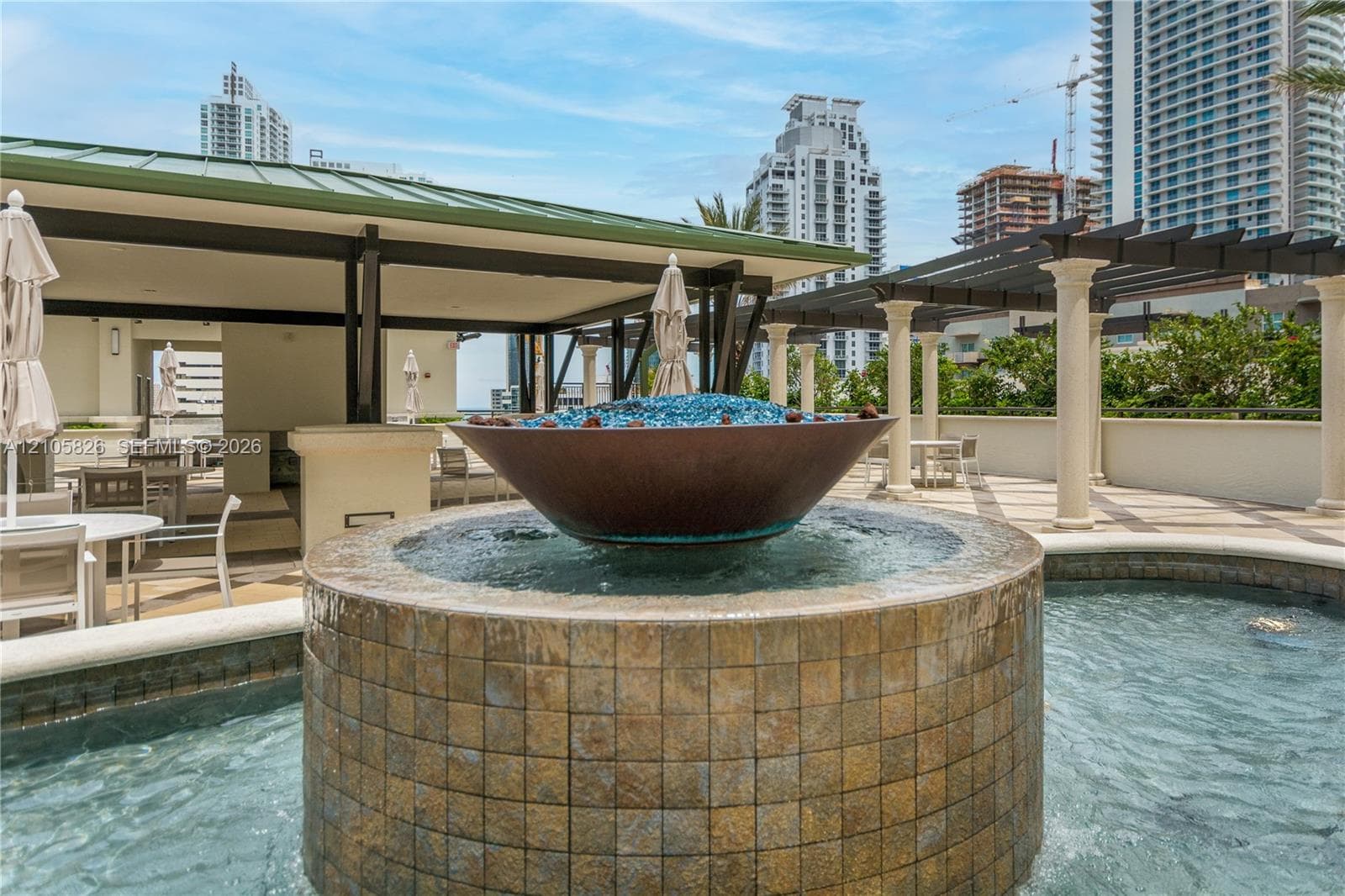Rooftop terrace featuring a tiled water fountain, metal fire bowl, covered pavilion with a metal roof, and stone-finished pergola