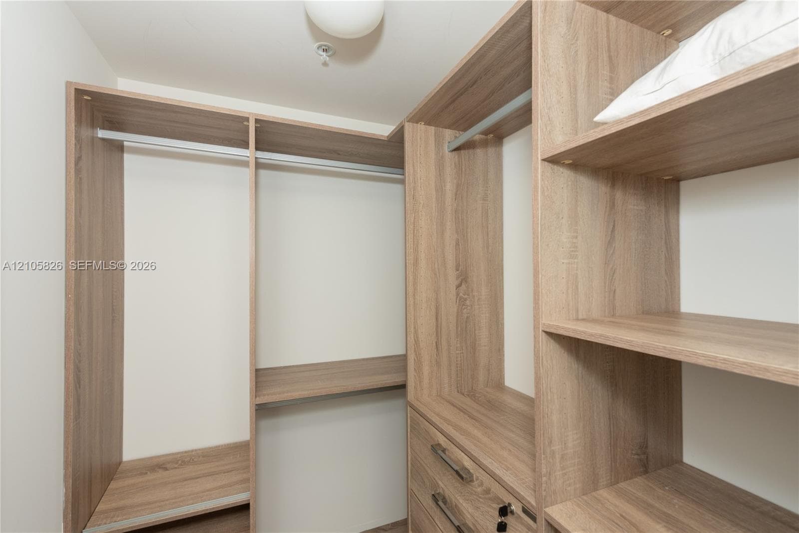 Custom wood-finish closet system featuring integrated shelving, hanging rods, and built-in drawers with metallic hardware