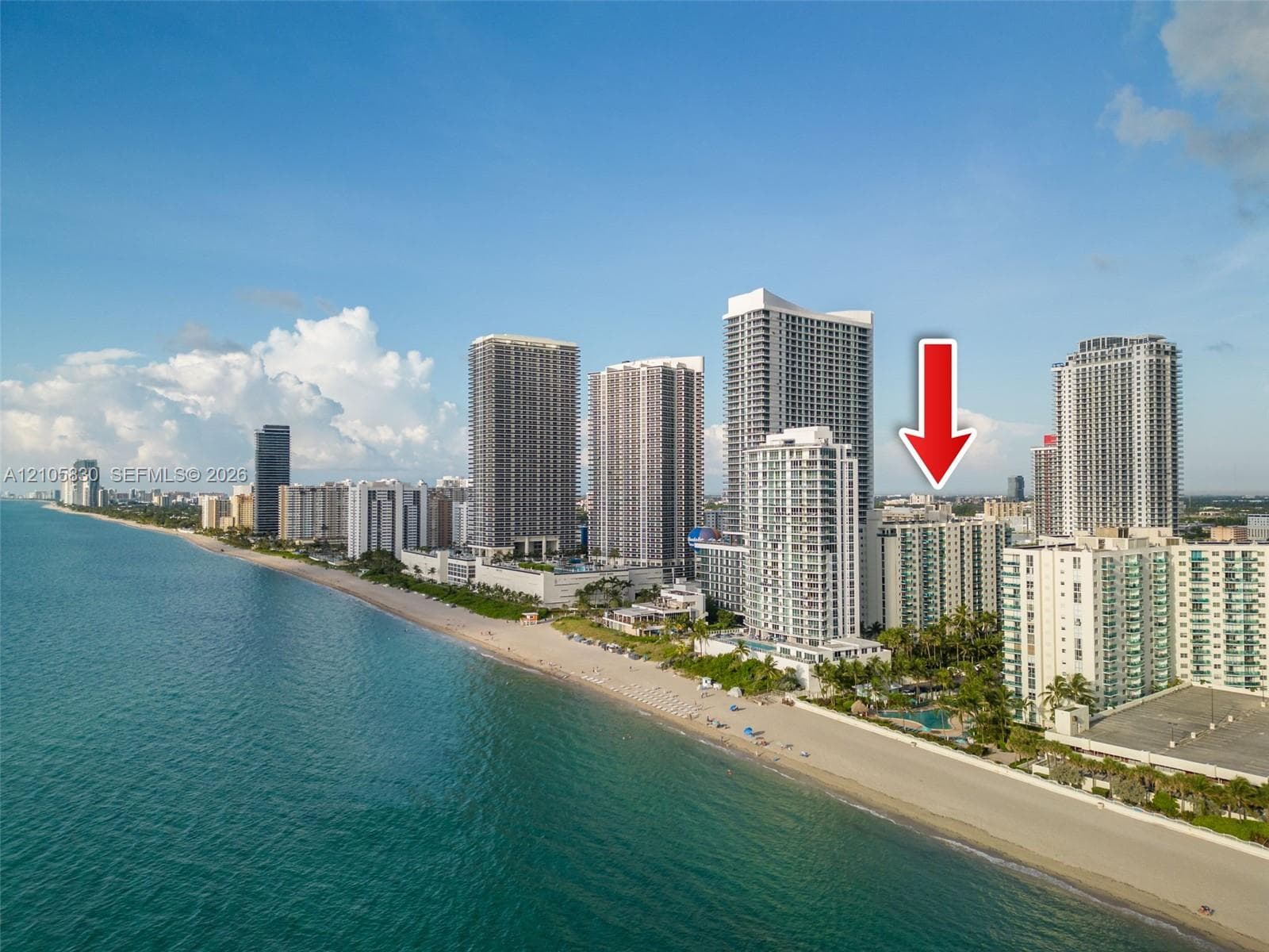 High-rise residential building situated along the coastal shoreline featuring direct proximity to the ocean and sandy beach
