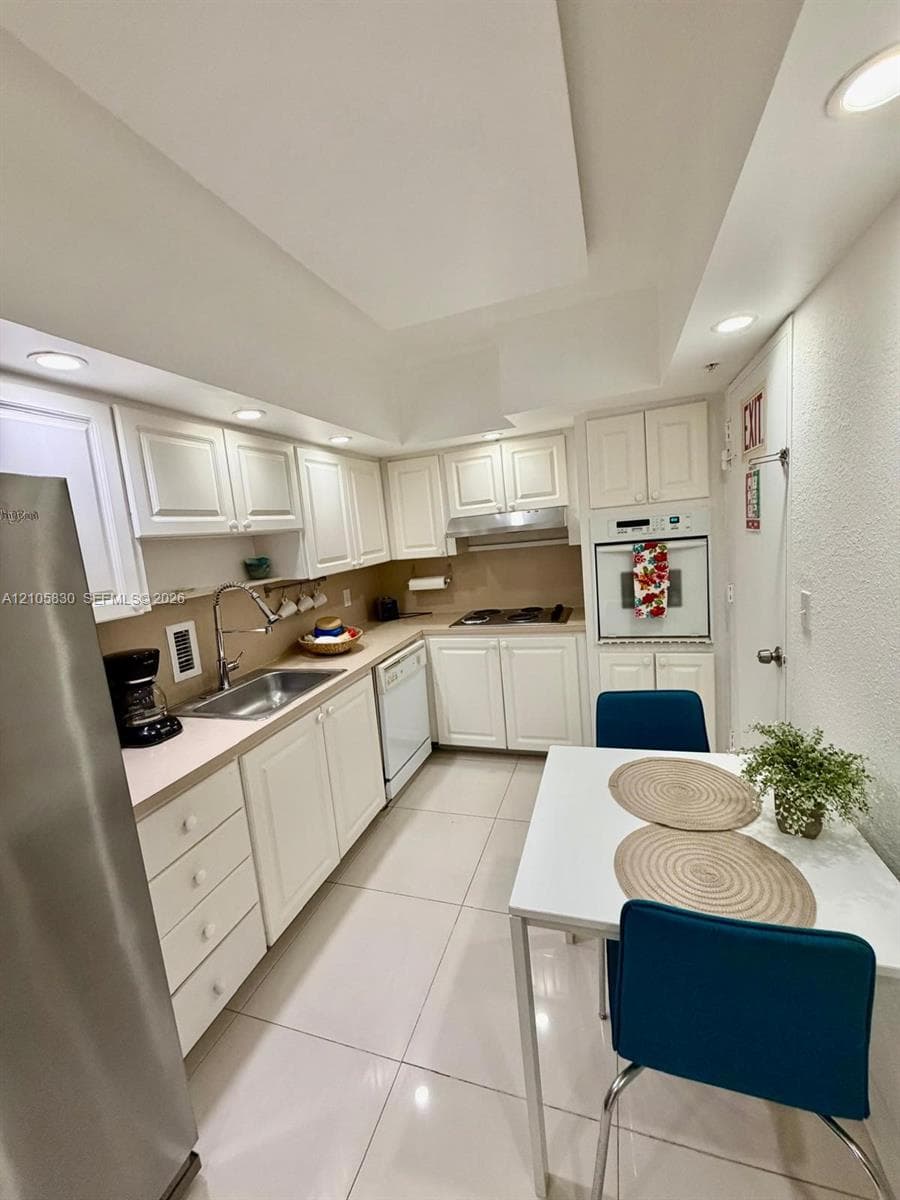 Kitchen featuring white cabinetry, stainless steel refrigerator, built-in oven, gas cooktop, and tile flooring