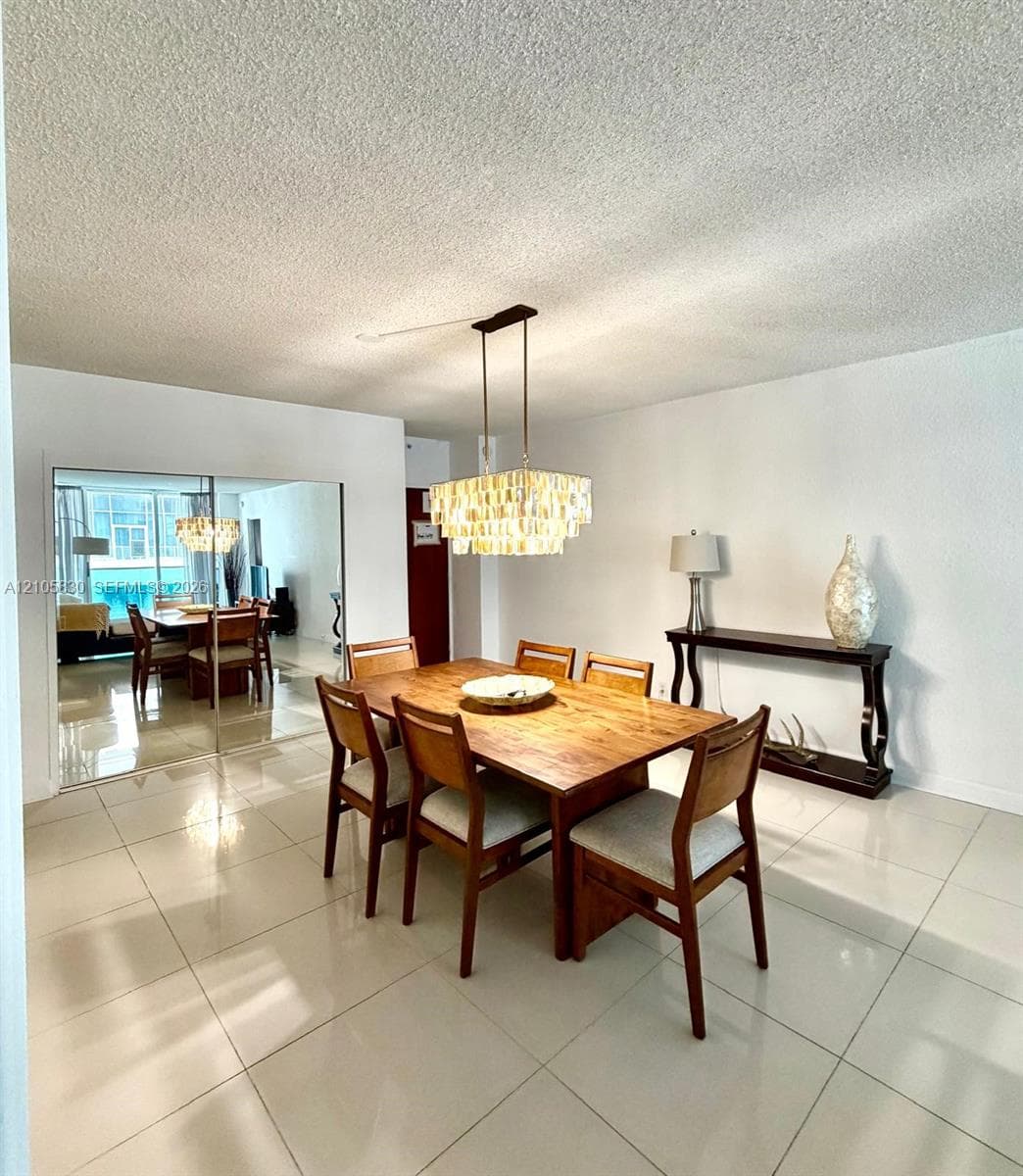 Large-format tile flooring, tiered crystal chandelier, and floor-to-ceiling mirrored closet doors